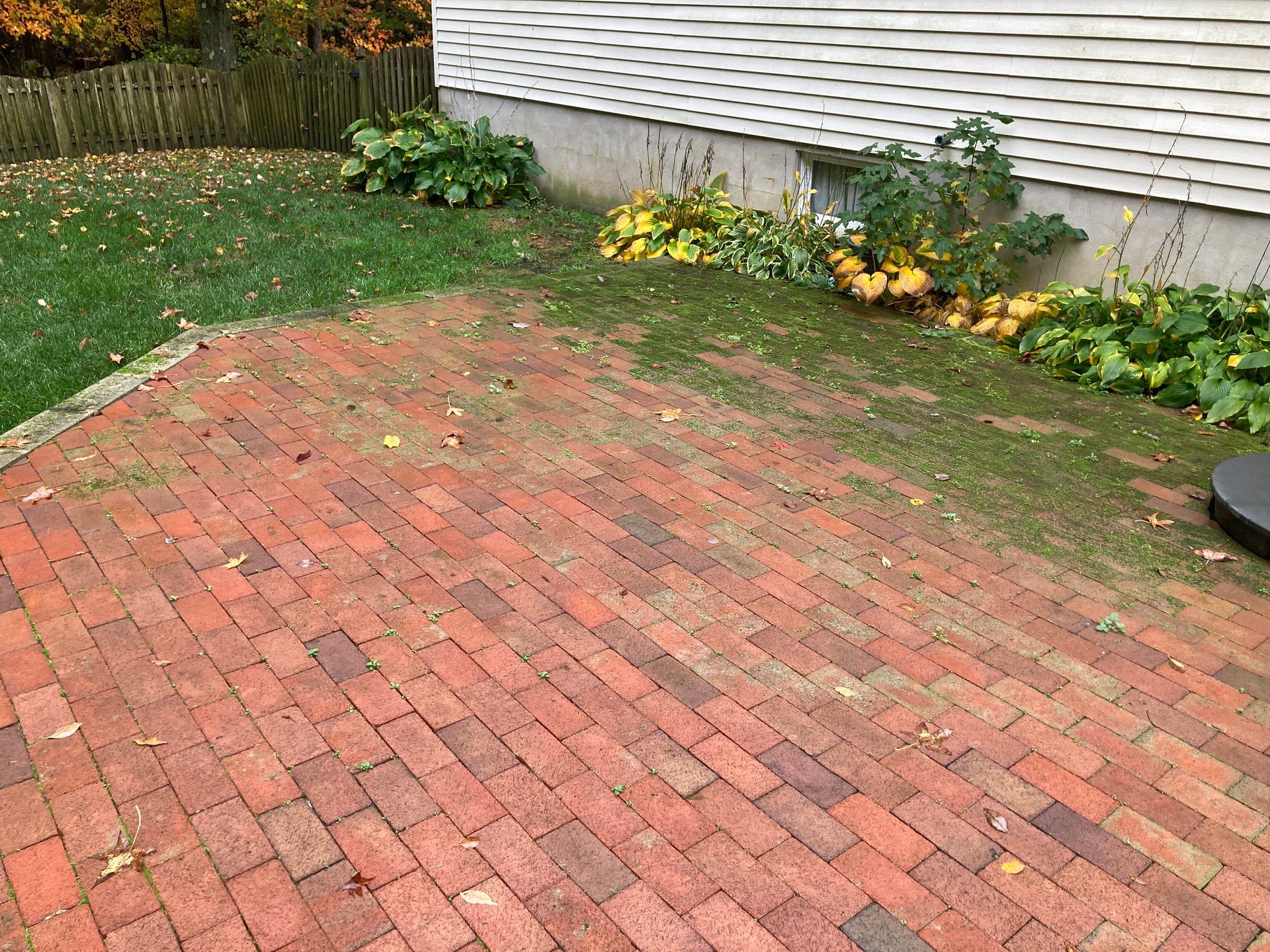 A red brick patio with a white house in the background.