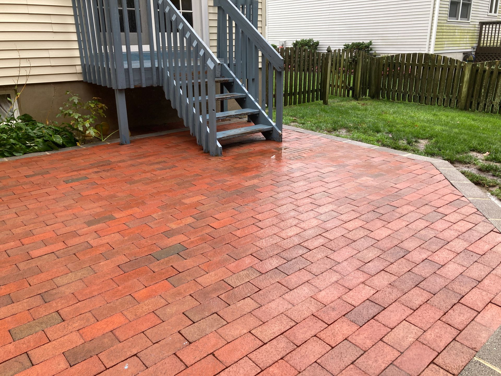 A brick patio with stairs leading up to a deck.