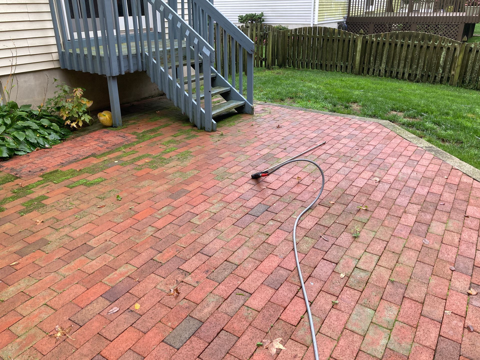 A brick patio with stairs and a hose attached to it.