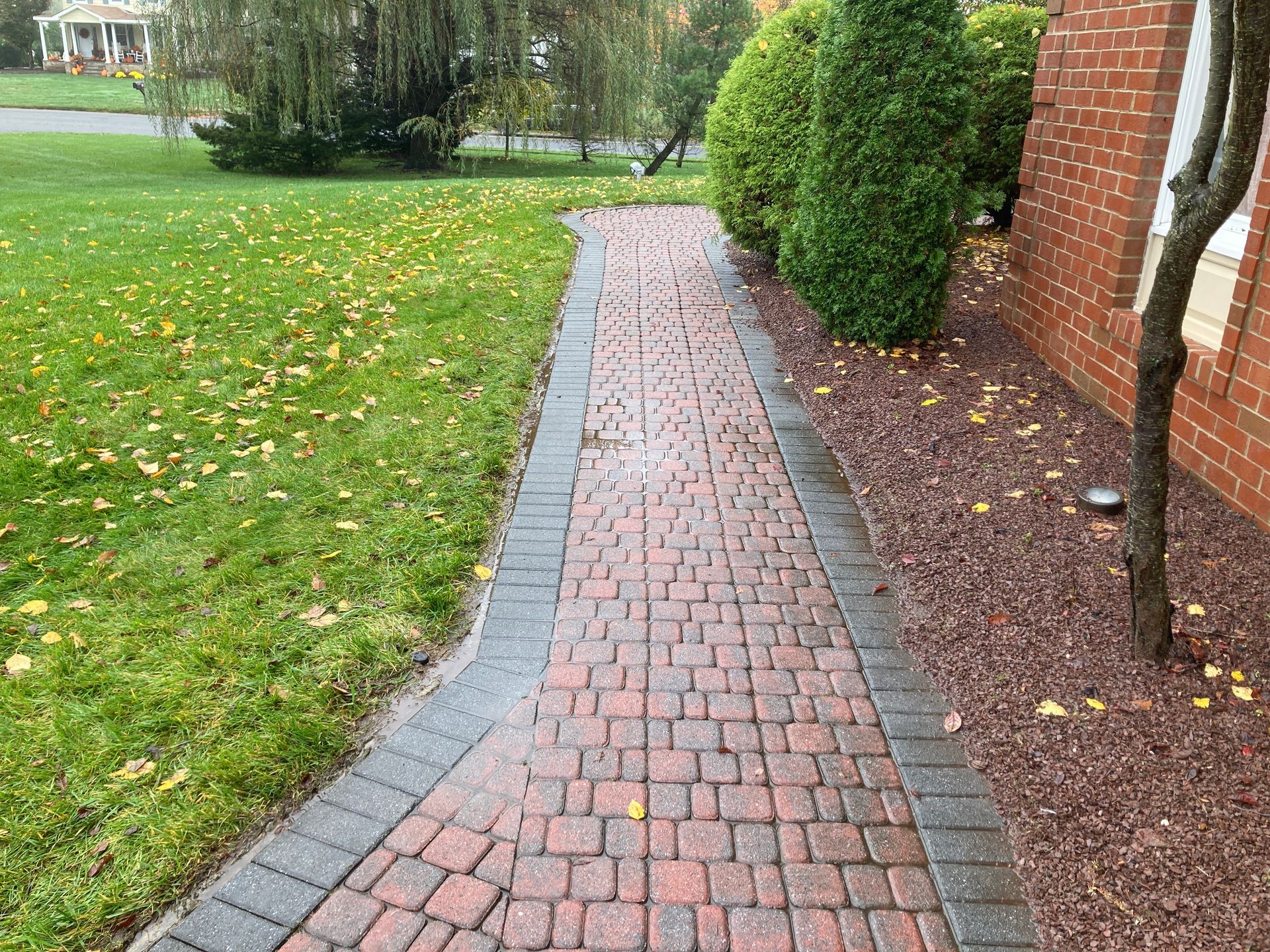 A brick walkway leading to a brick house.