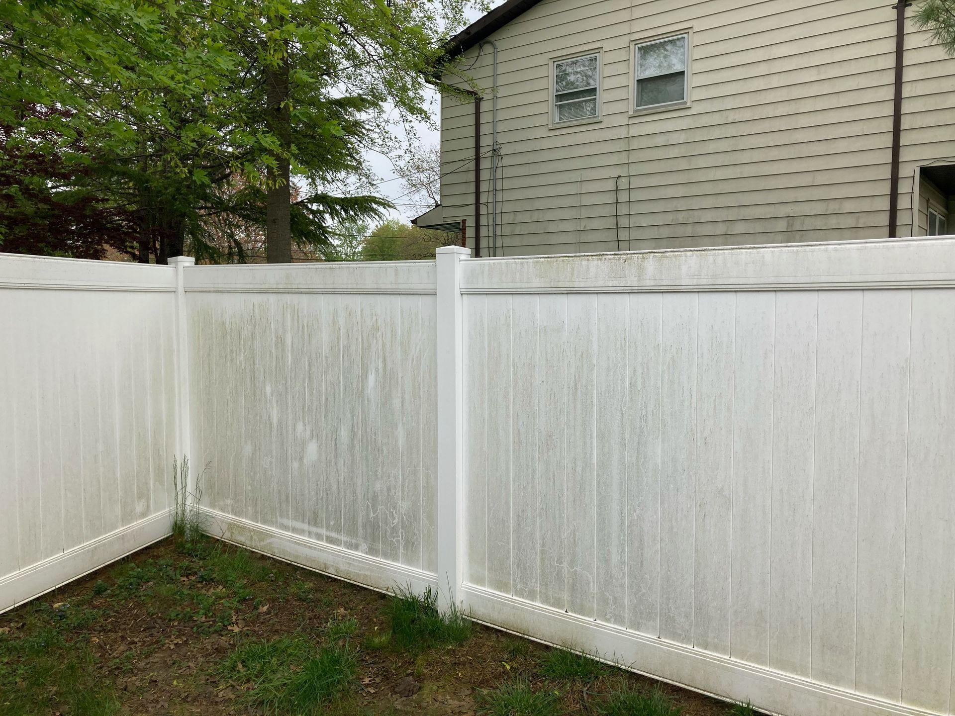 A white fence is sitting in the grass in front of a house.