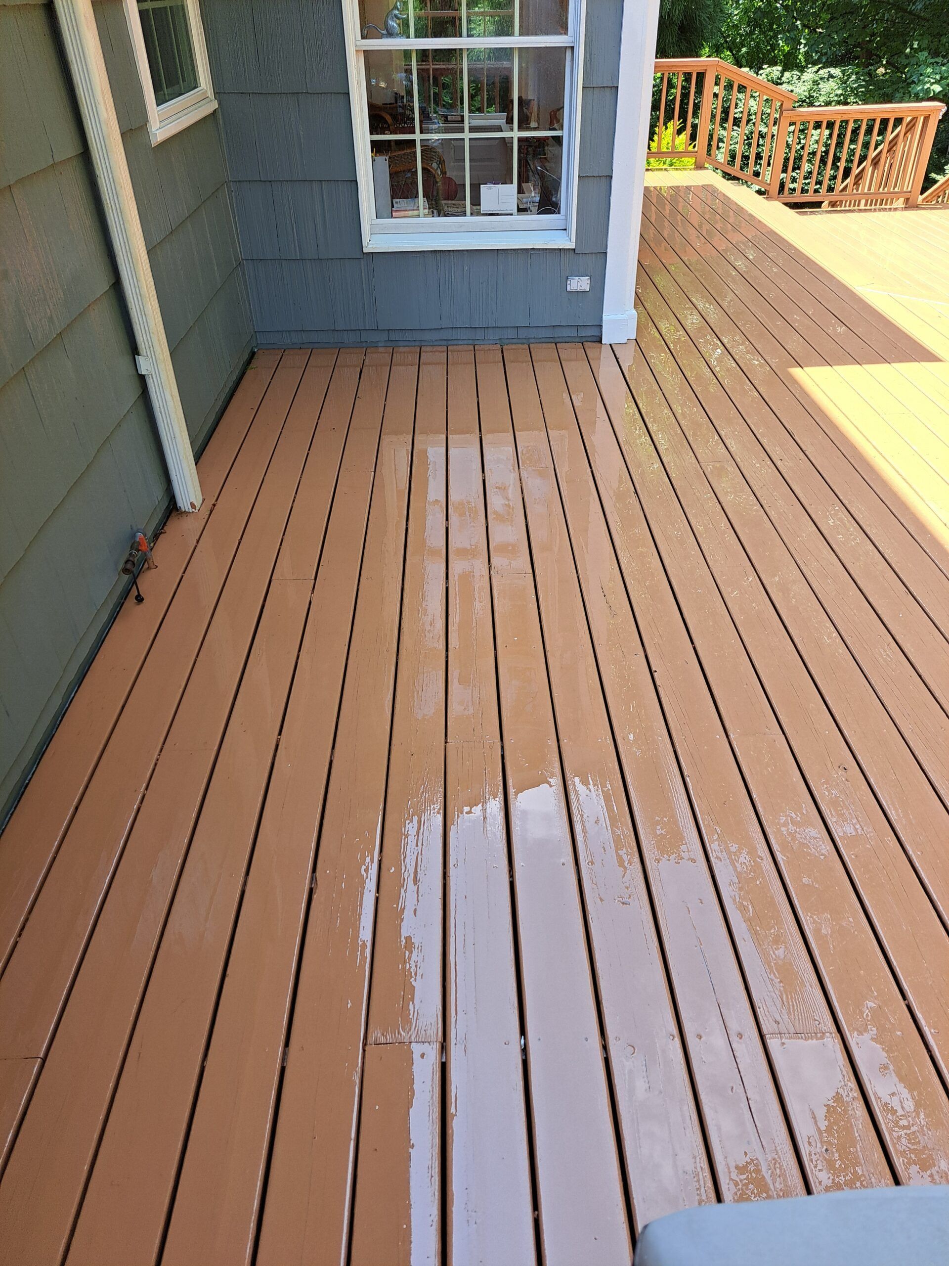 A wooden deck with a window on the side of a house.