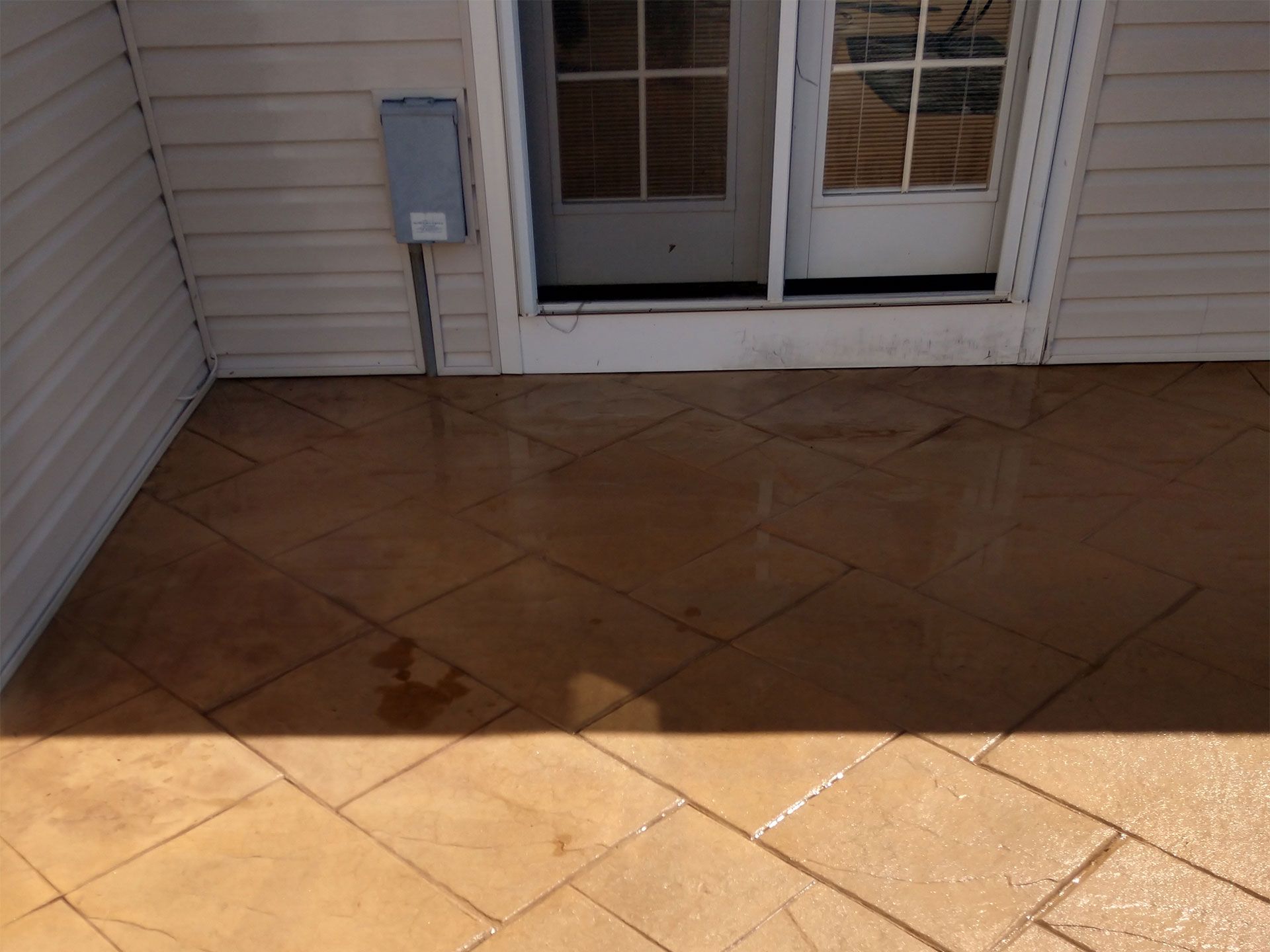 A tiled floor in front of a house with a sliding glass door