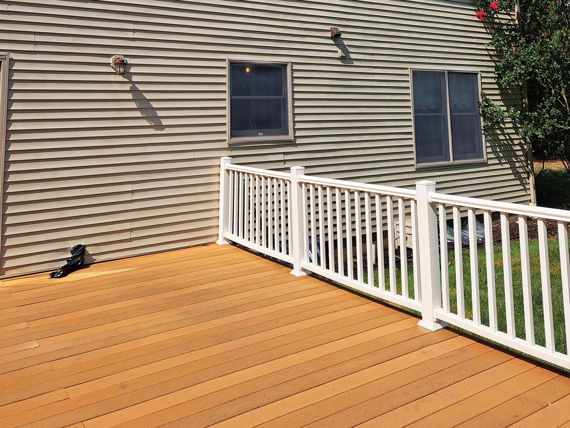A wooden deck with a white railing in front of a house.