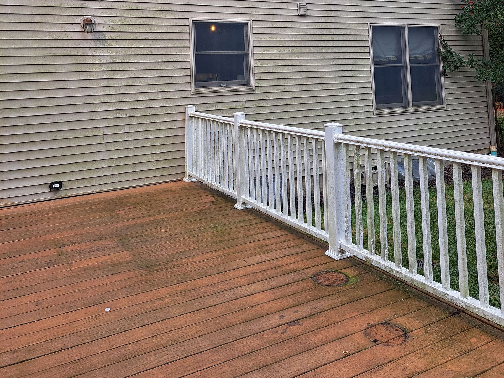 A wooden deck with a white railing in front of a house.