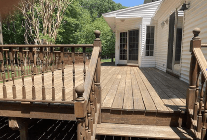 A wooden deck with stairs leading to a white house.