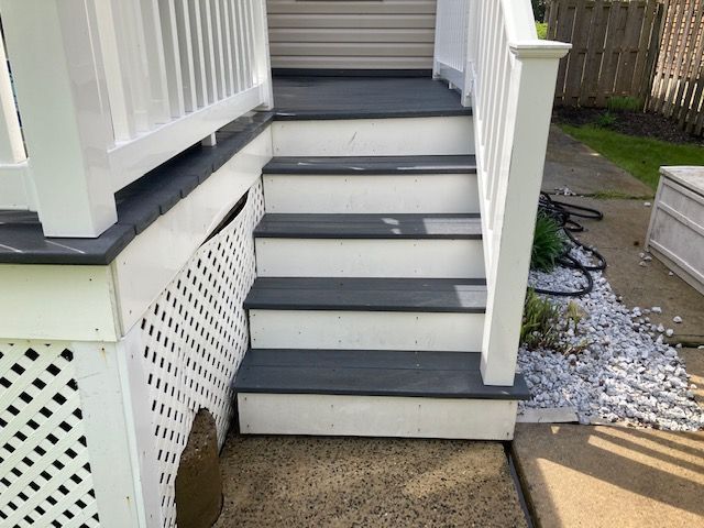 A set of stairs leading up to a porch with a white railing.