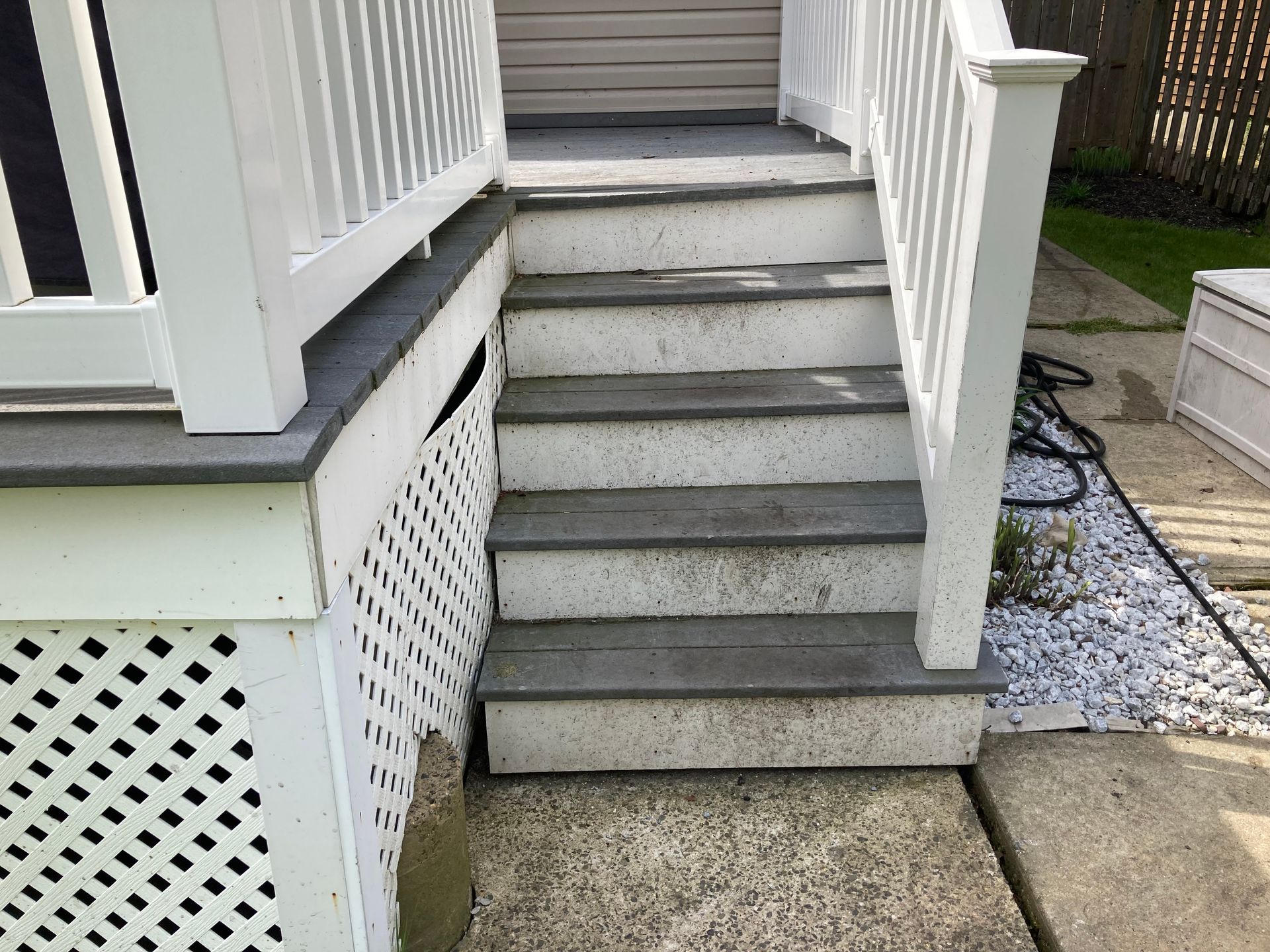 A set of stairs leading up to a porch with a white railing.