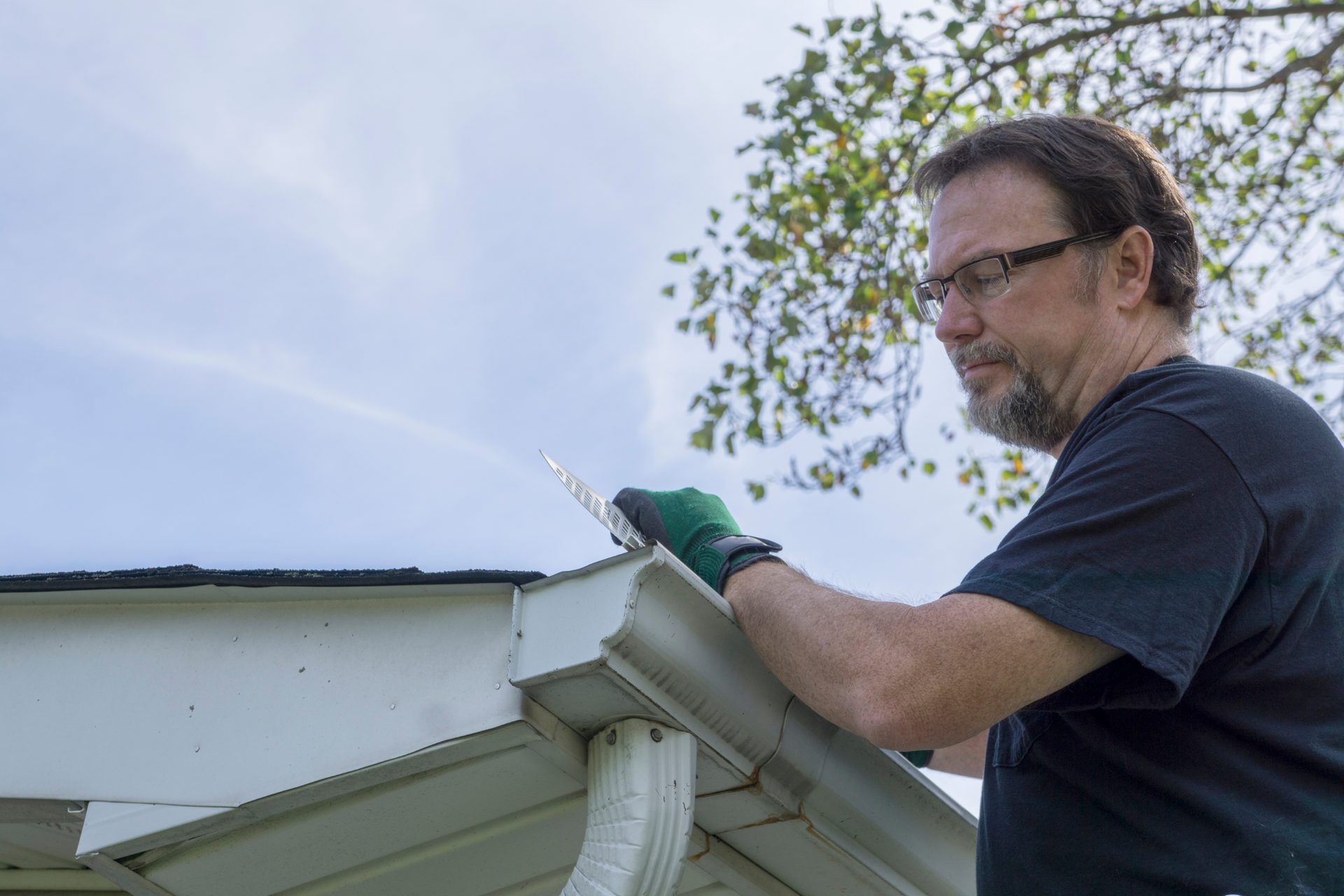 A man is working on a gutter guard.