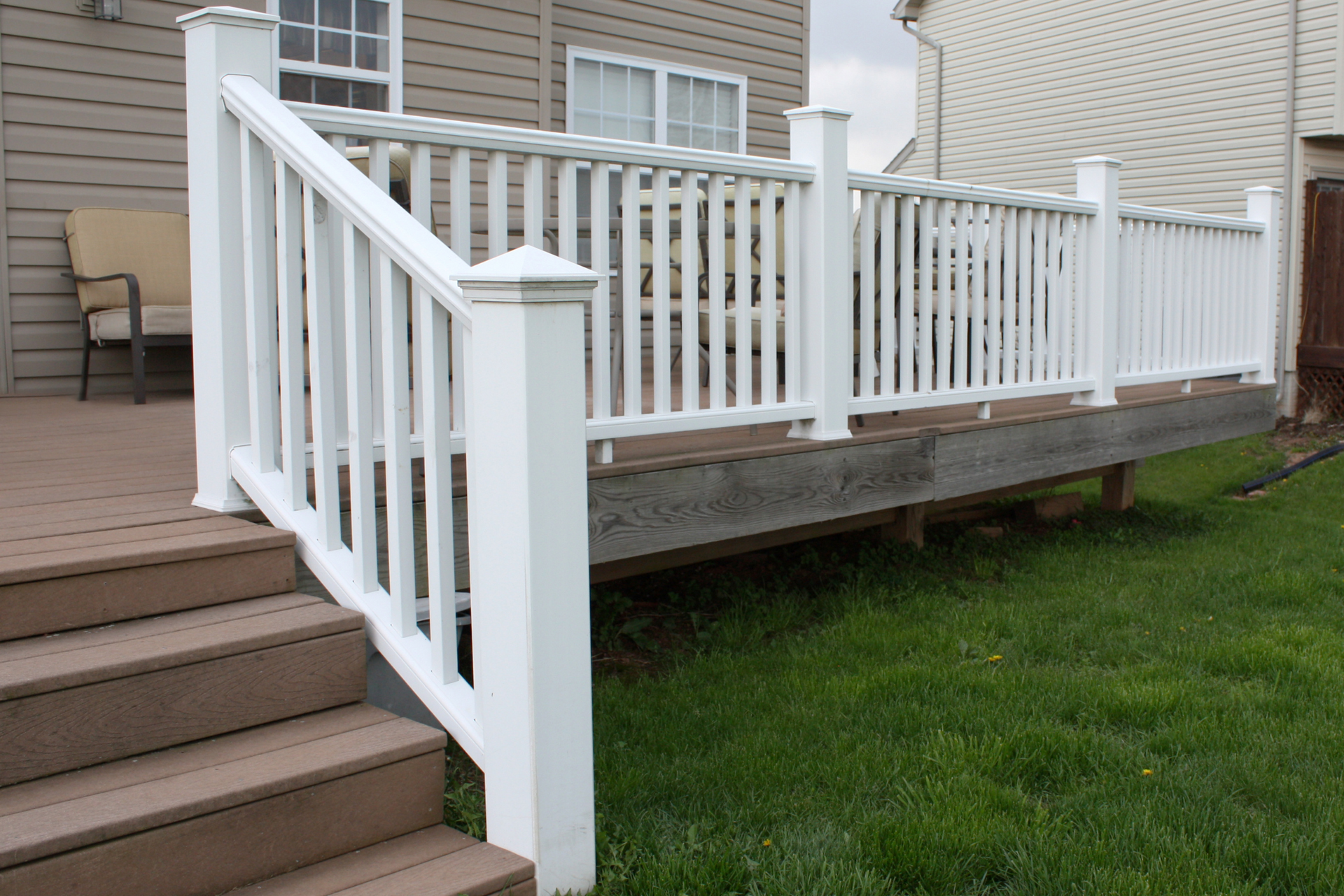 A white railing on a Trex deck with stairs after powerwashing.