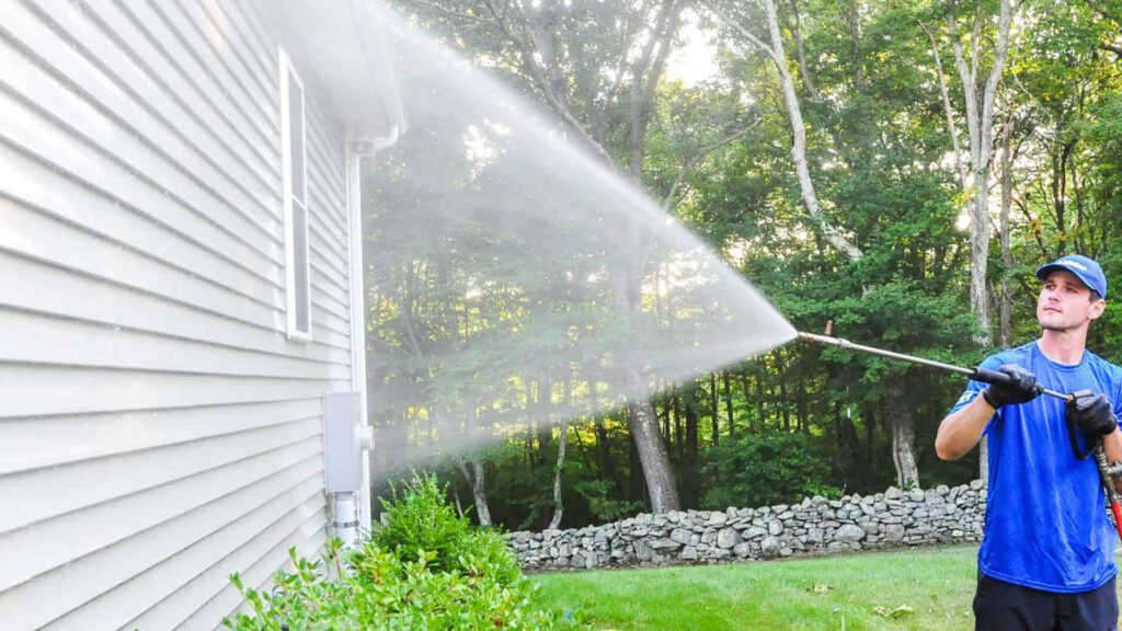 Man using a soft wash system to clean siding in Manalapan, NJ.07726