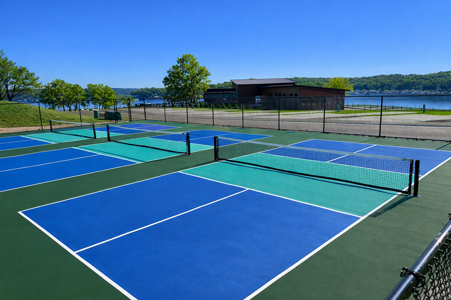 Swimming pool and clubhouse at an RV resort. Black asphalt, green grass, and clear blue water.