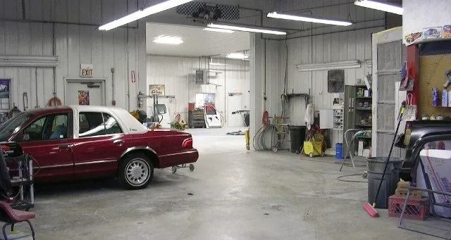 Red car in an auto repair garage with tools, equipment, and open work bays