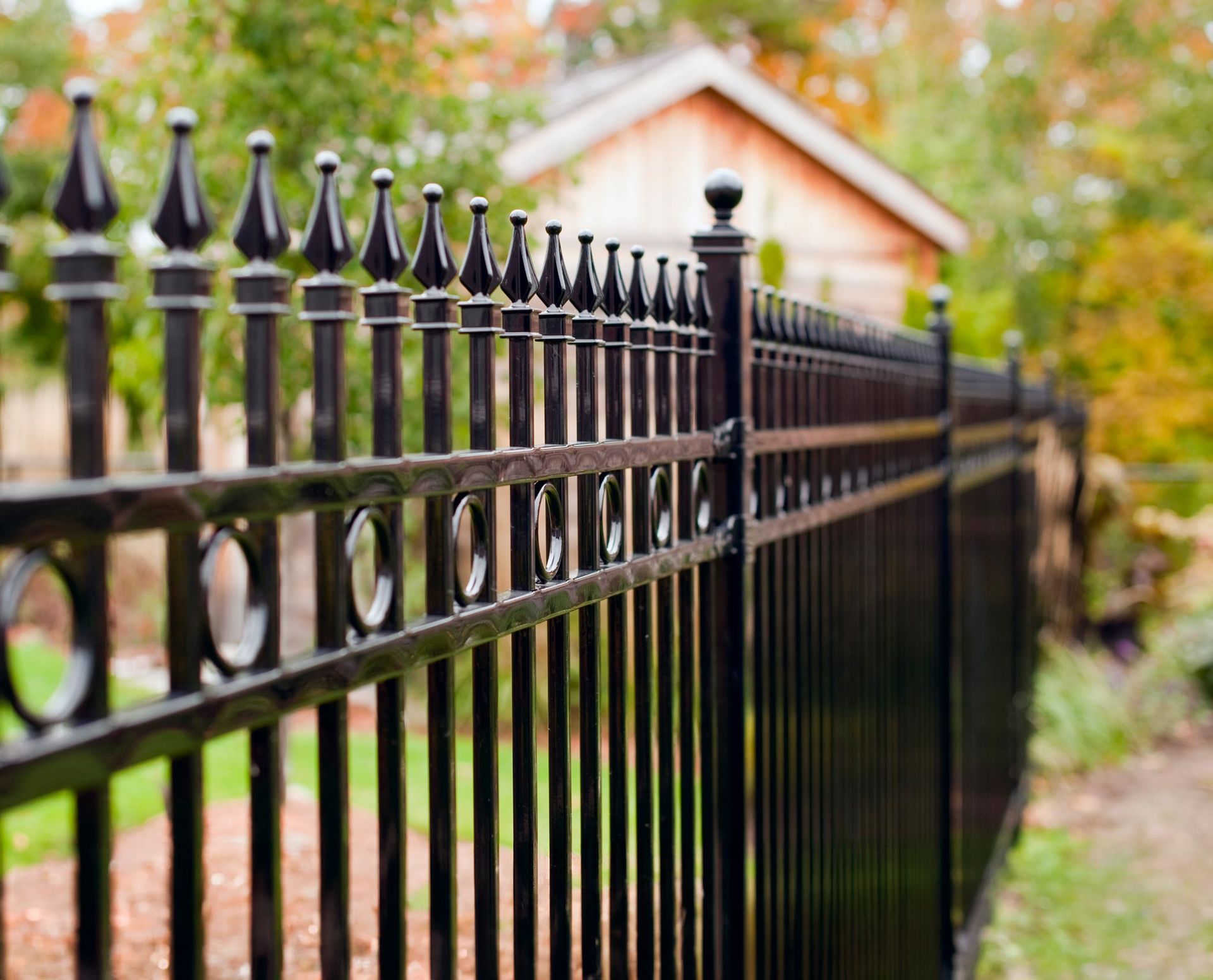 A black wrought iron fence with a house in the background. A black wrought iron fence with a house in the background.