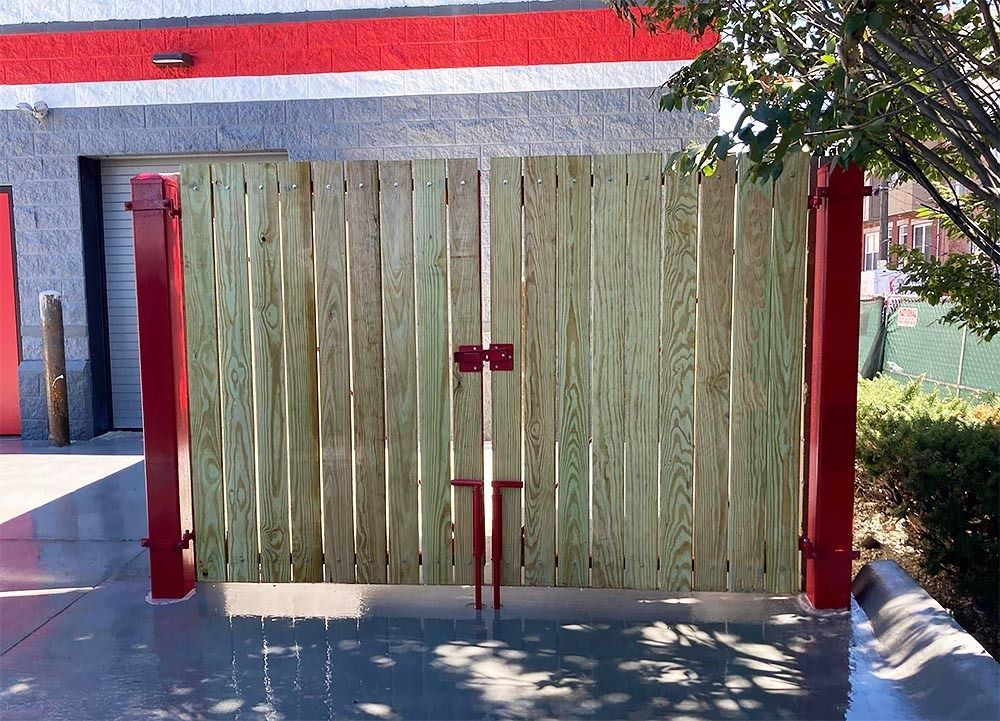 A wooden fence with a red post in front of a building
