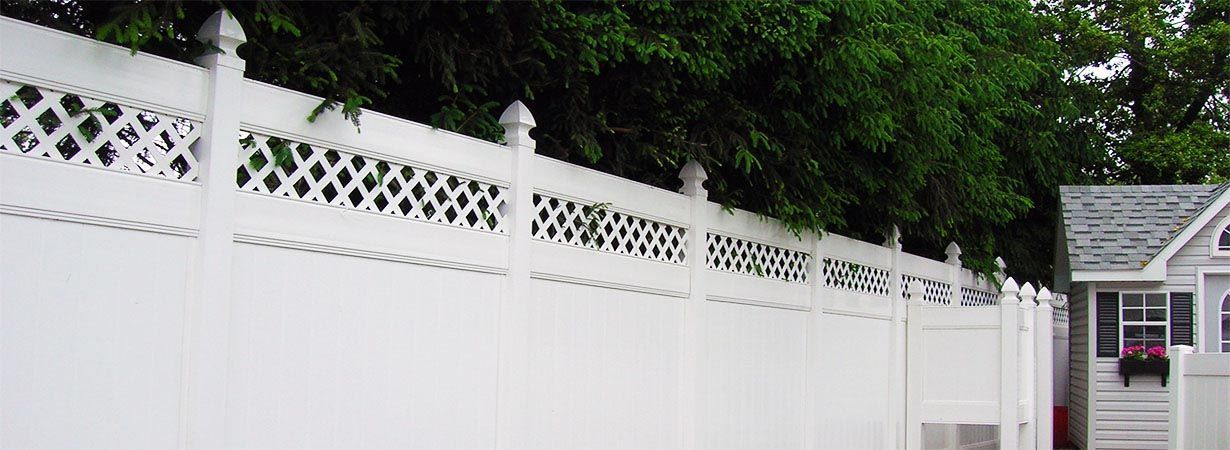 A white fence surrounds a small white house.