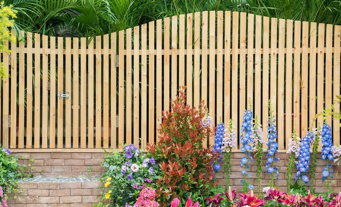 A wooden fence is surrounded by flowers in a garden.