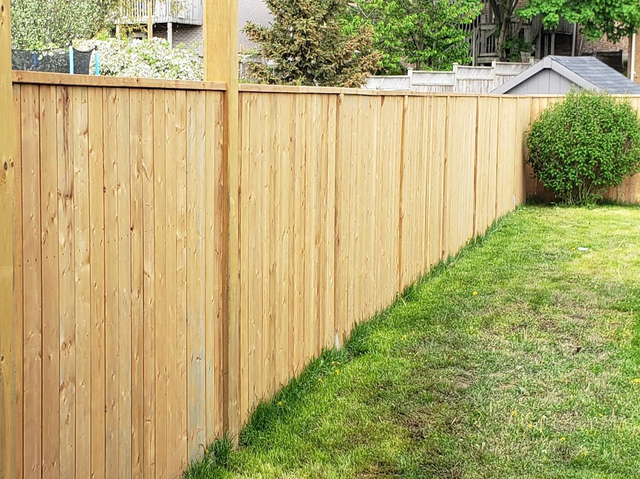 A wooden fence surrounds a lush green yard.