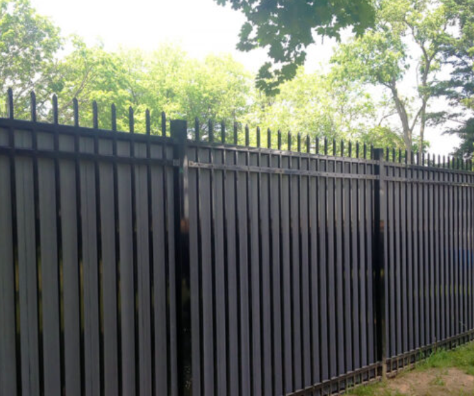 A black metal fence with trees in the background.