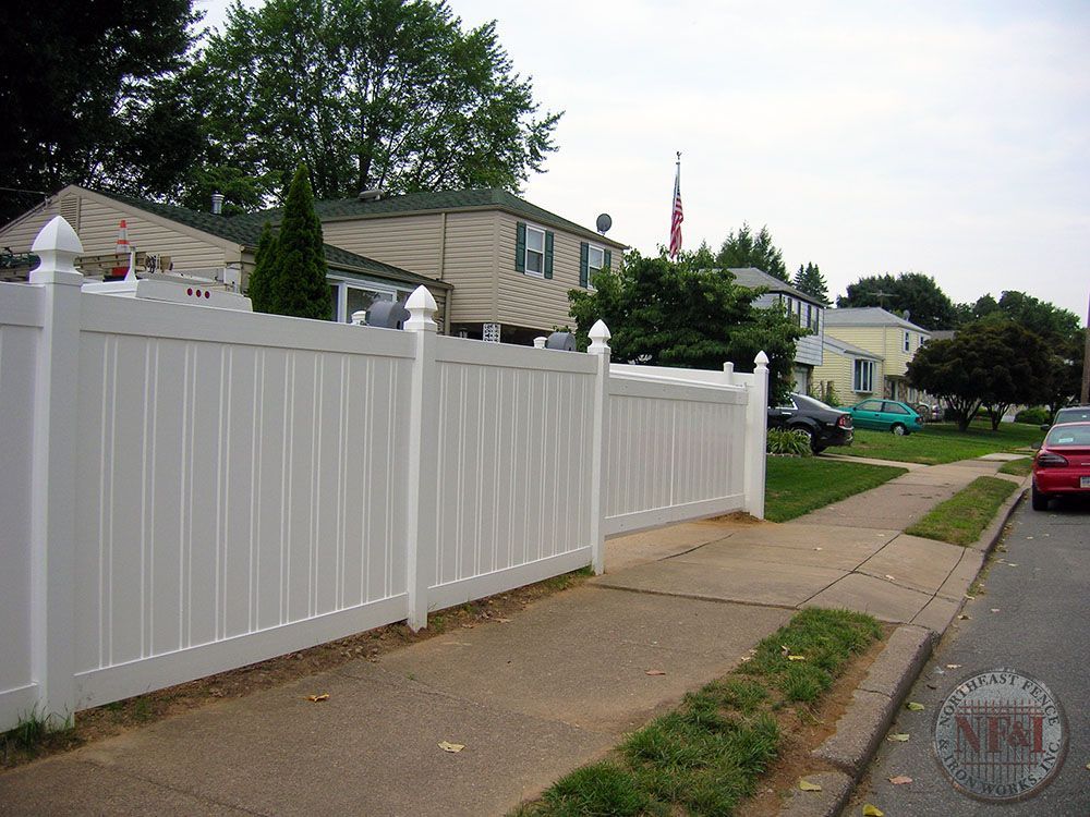 A white fence along a sidewalk in a residential neighborhood