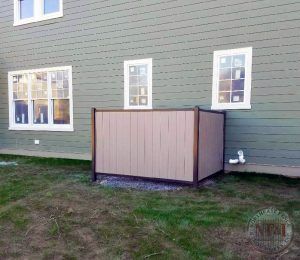 A wooden box is sitting in the grass in front of a house.