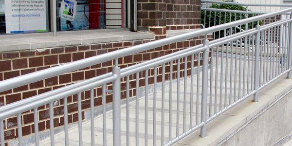 A metal railing surrounds a ramp leading to a brick building.