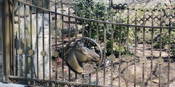 A wrought iron gate with a horse head on it.
