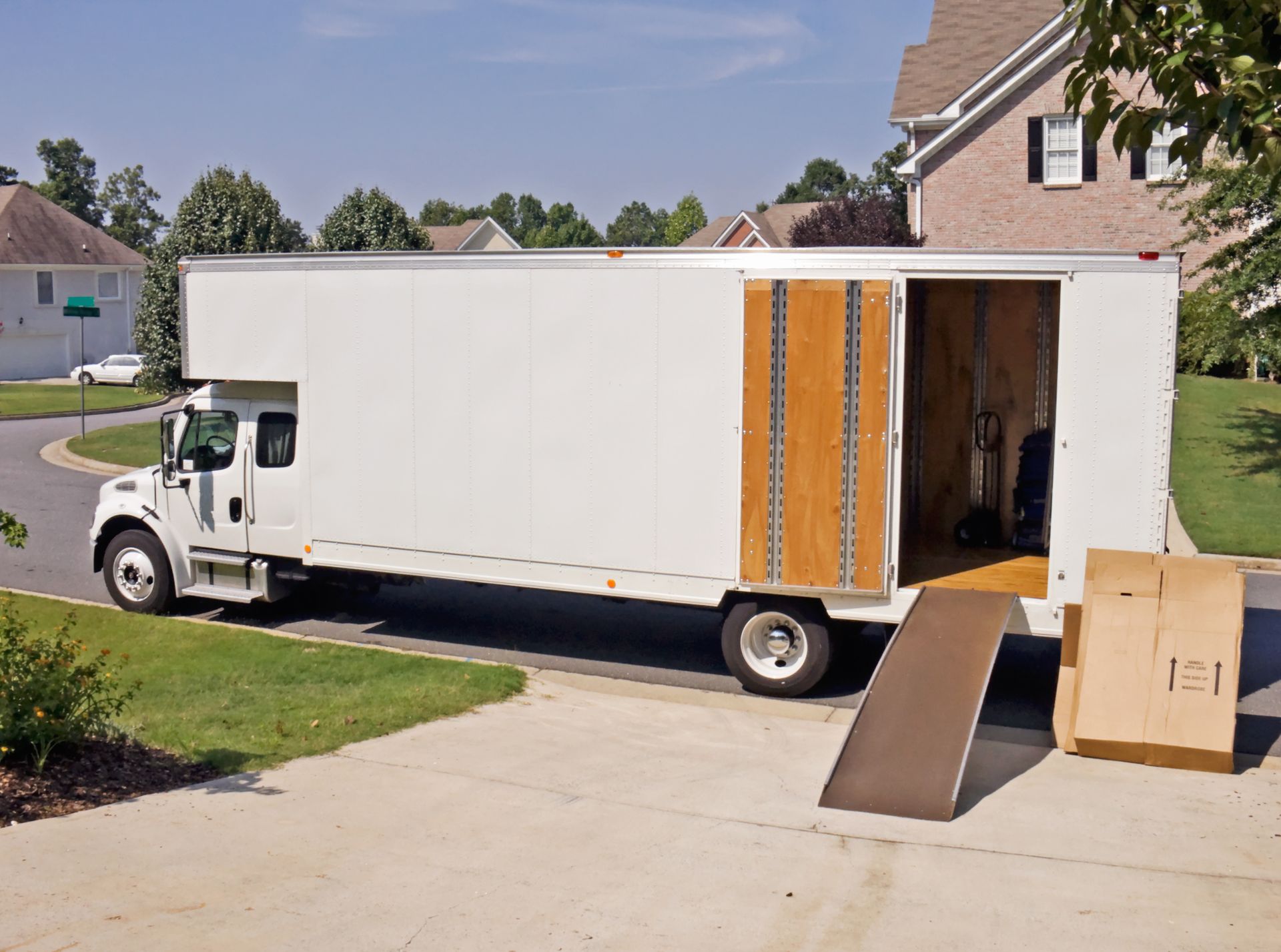 Un camion de déménagement blanc est garé devant une maison