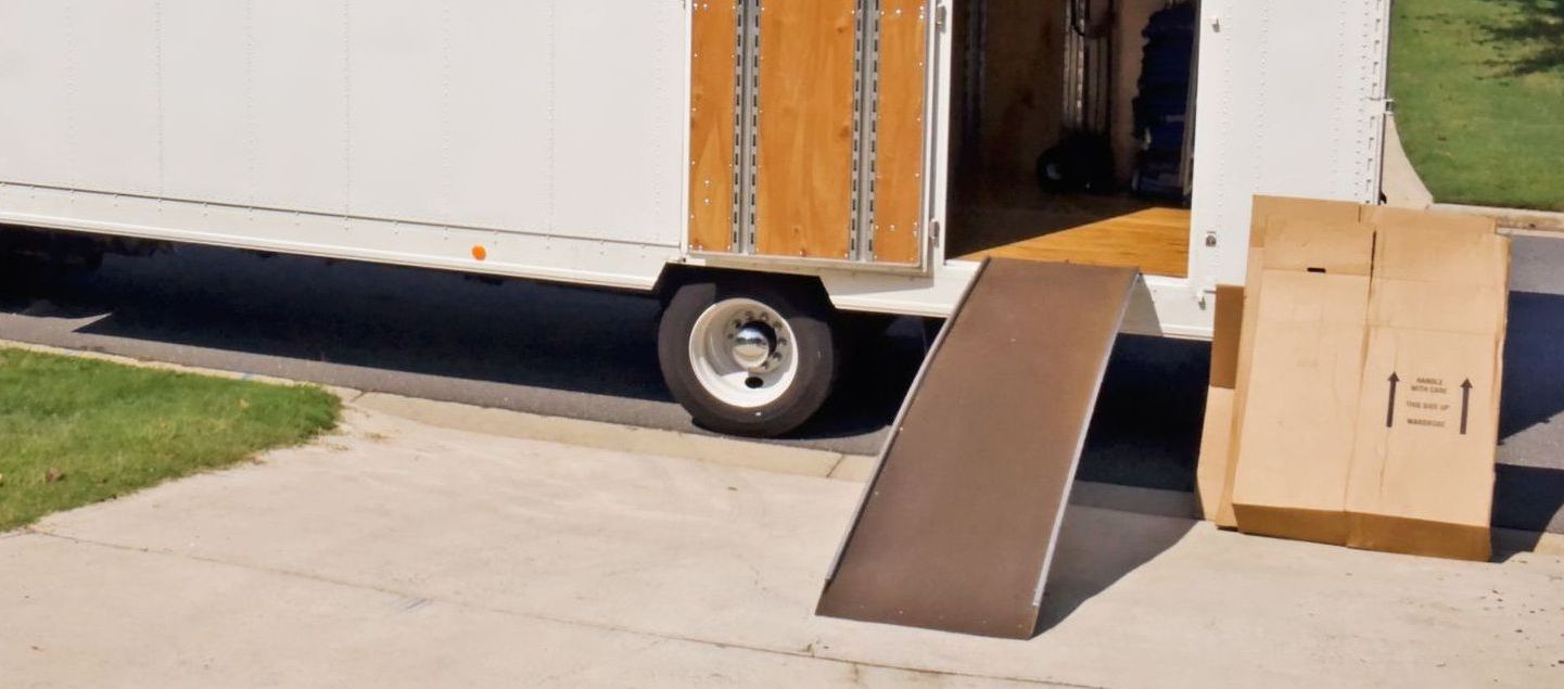Un camion de déménagement est garé sur le bord de la route à côté d'une boîte en carton.