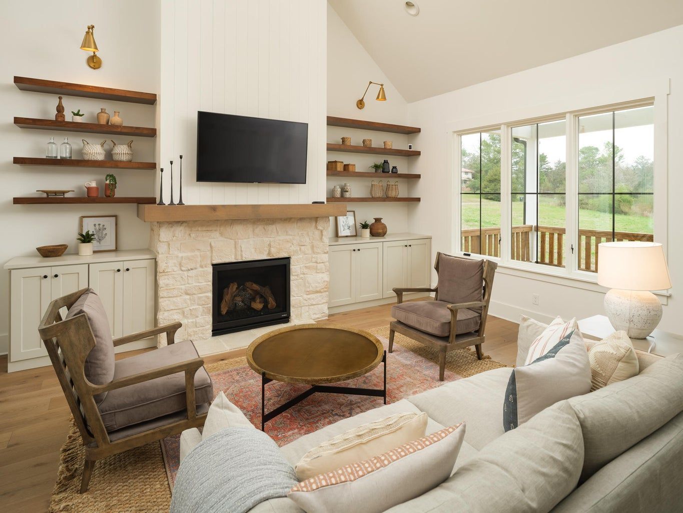 A living room with a fireplace , couch , chairs and a flat screen tv.