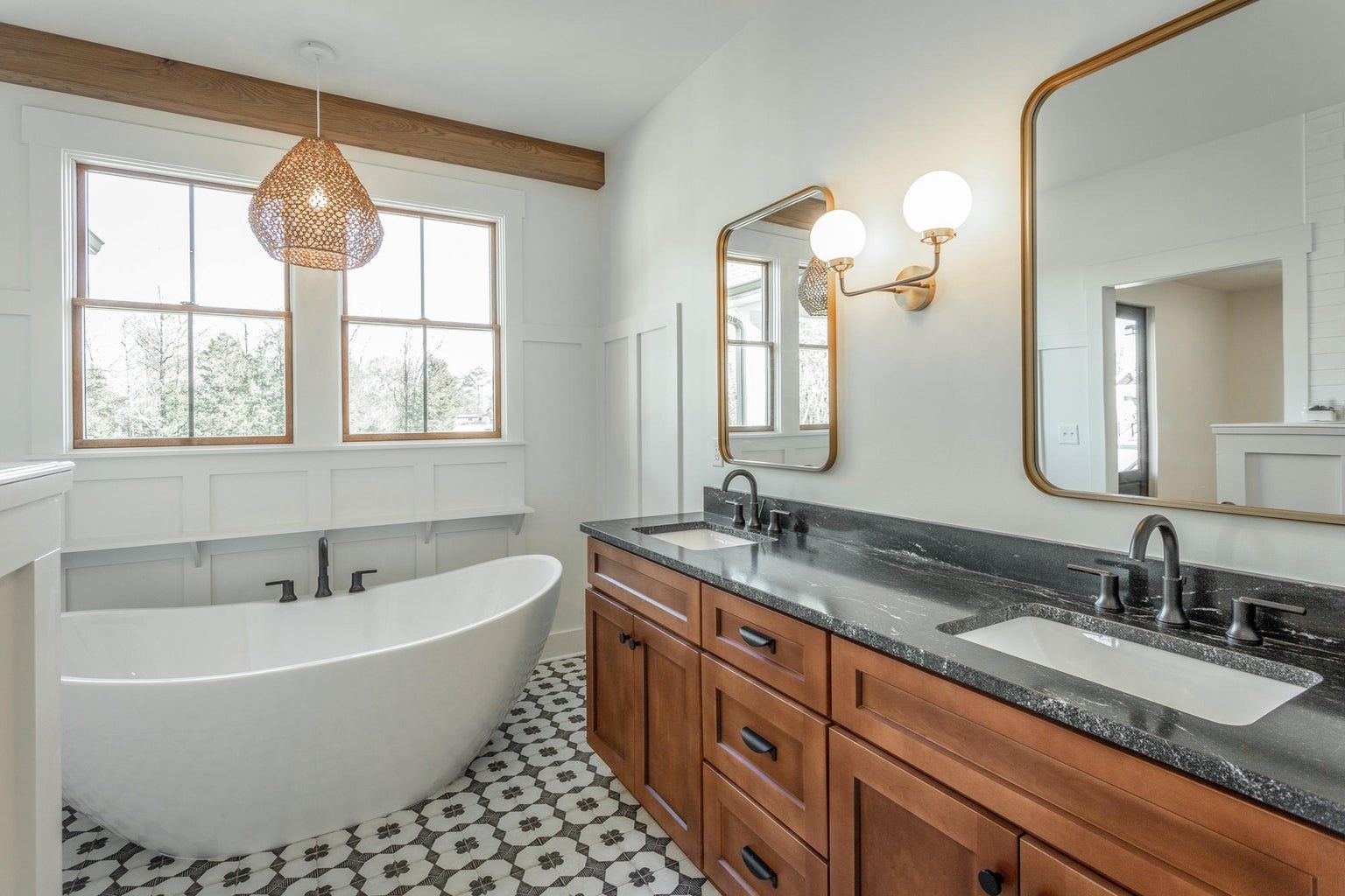 A bathroom with two sinks , a tub , and two mirrors.