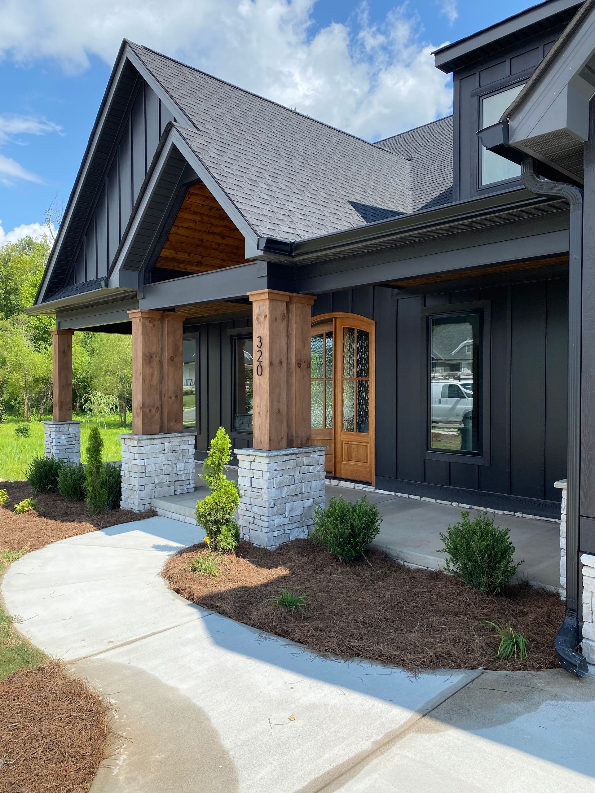 A large black house with a wooden porch and a walkway leading to it.