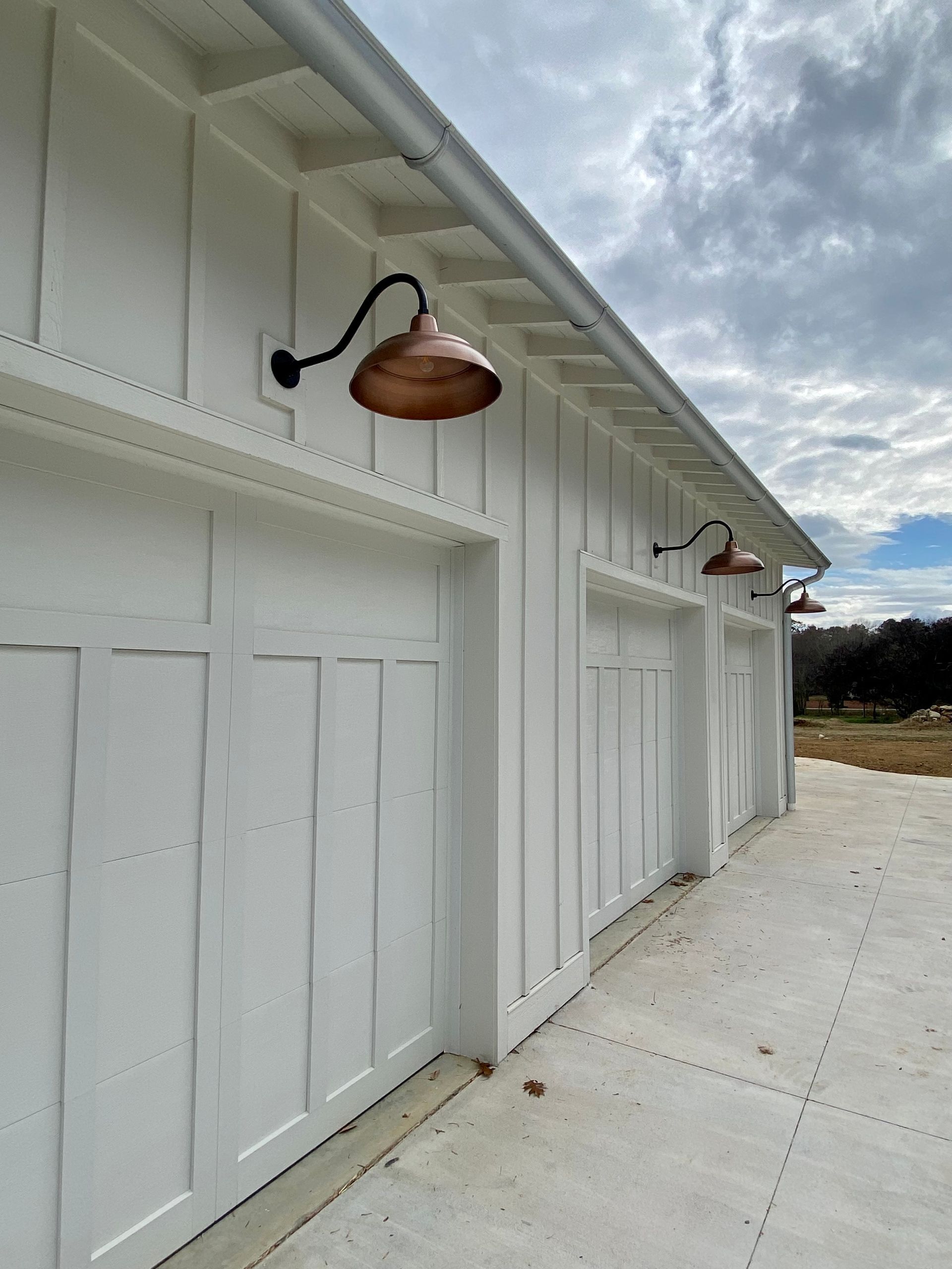 A row of white garage doors with copper lights on them.