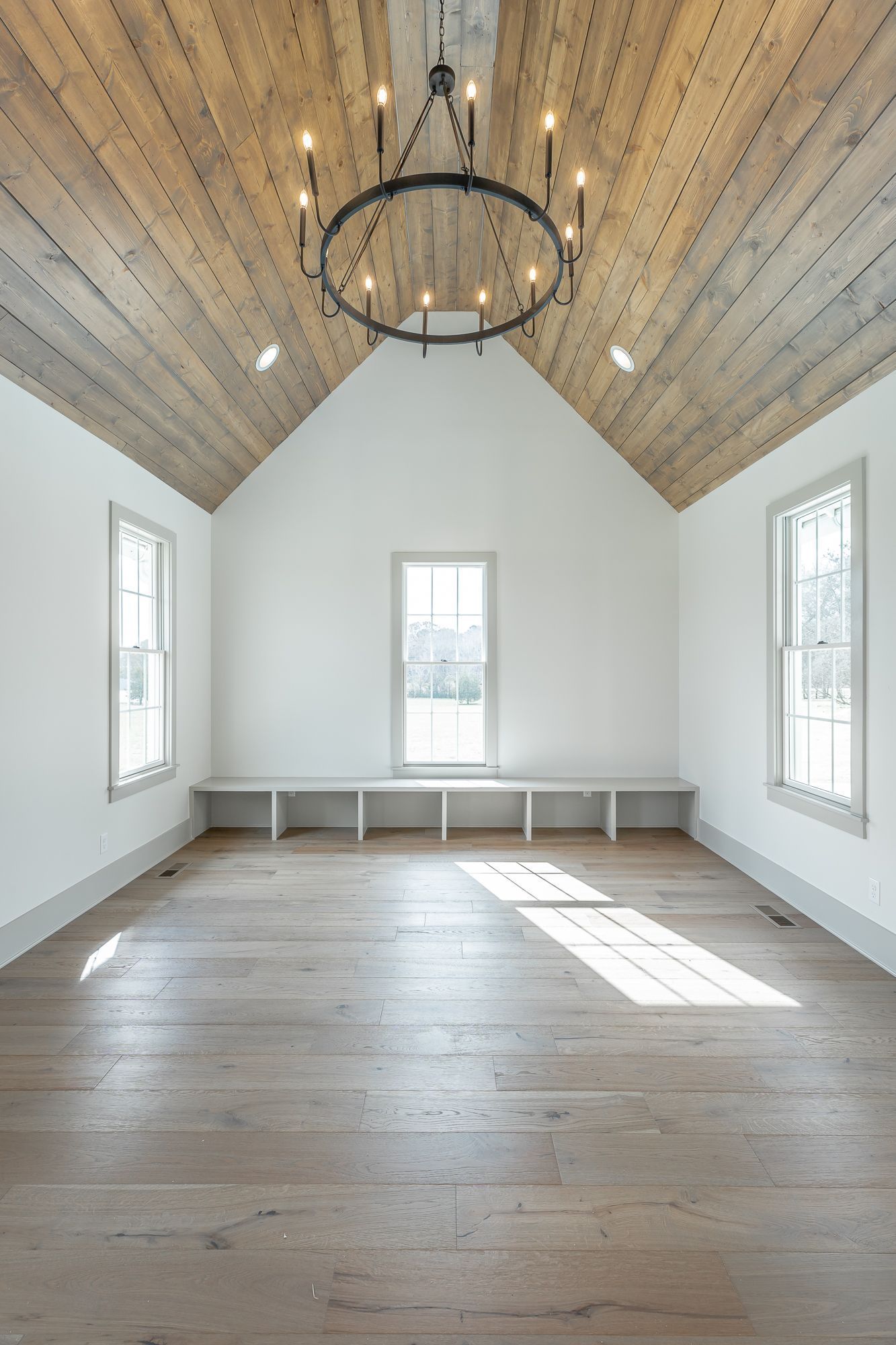 An empty room with a wooden ceiling and a chandelier.