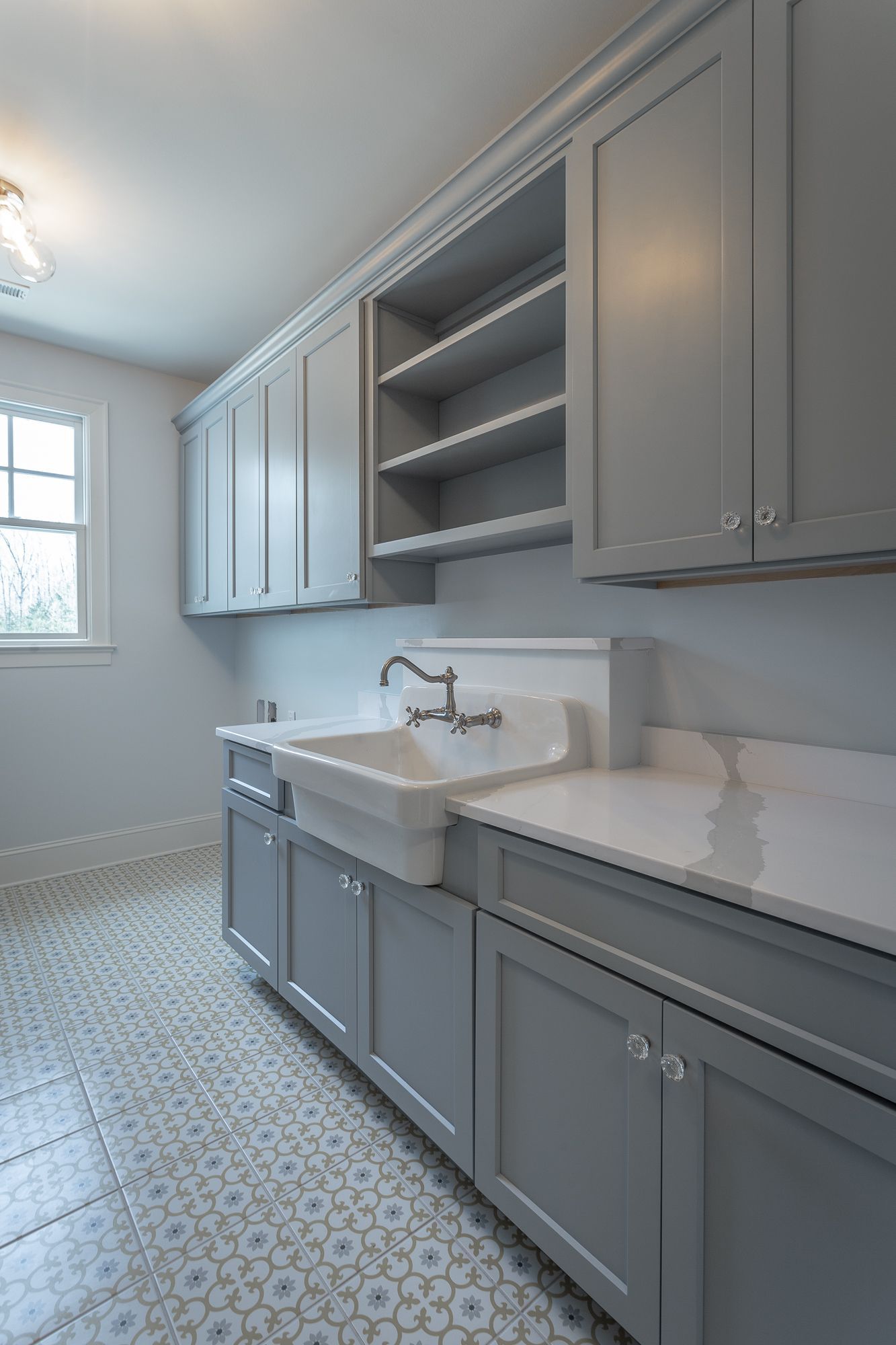 a laundry room with gray cabinets and a white sink .