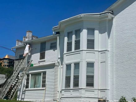 White Victorian house with bay windows and a fire escape under a clear blue sky