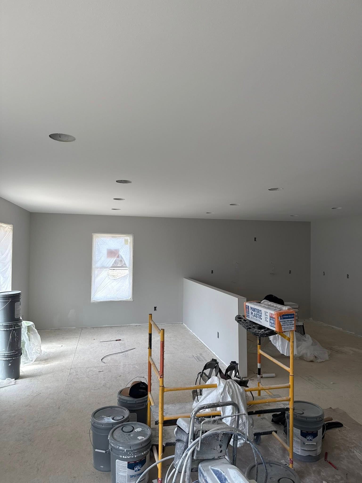 Unfinished room with drywall, scattered tools, and construction equipment on a bare floor