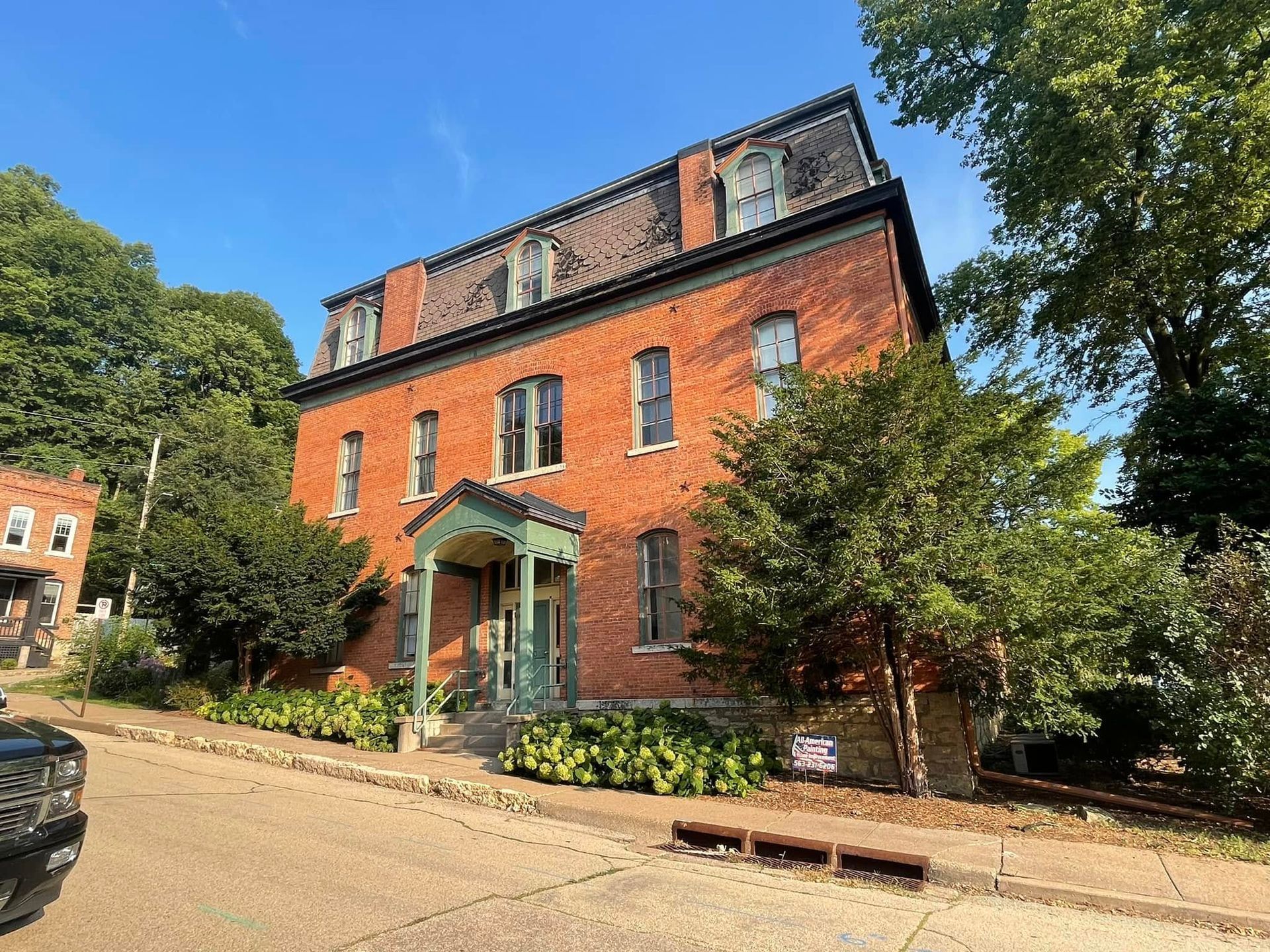 Red-brick building with green entrance awning on a tree-lined street