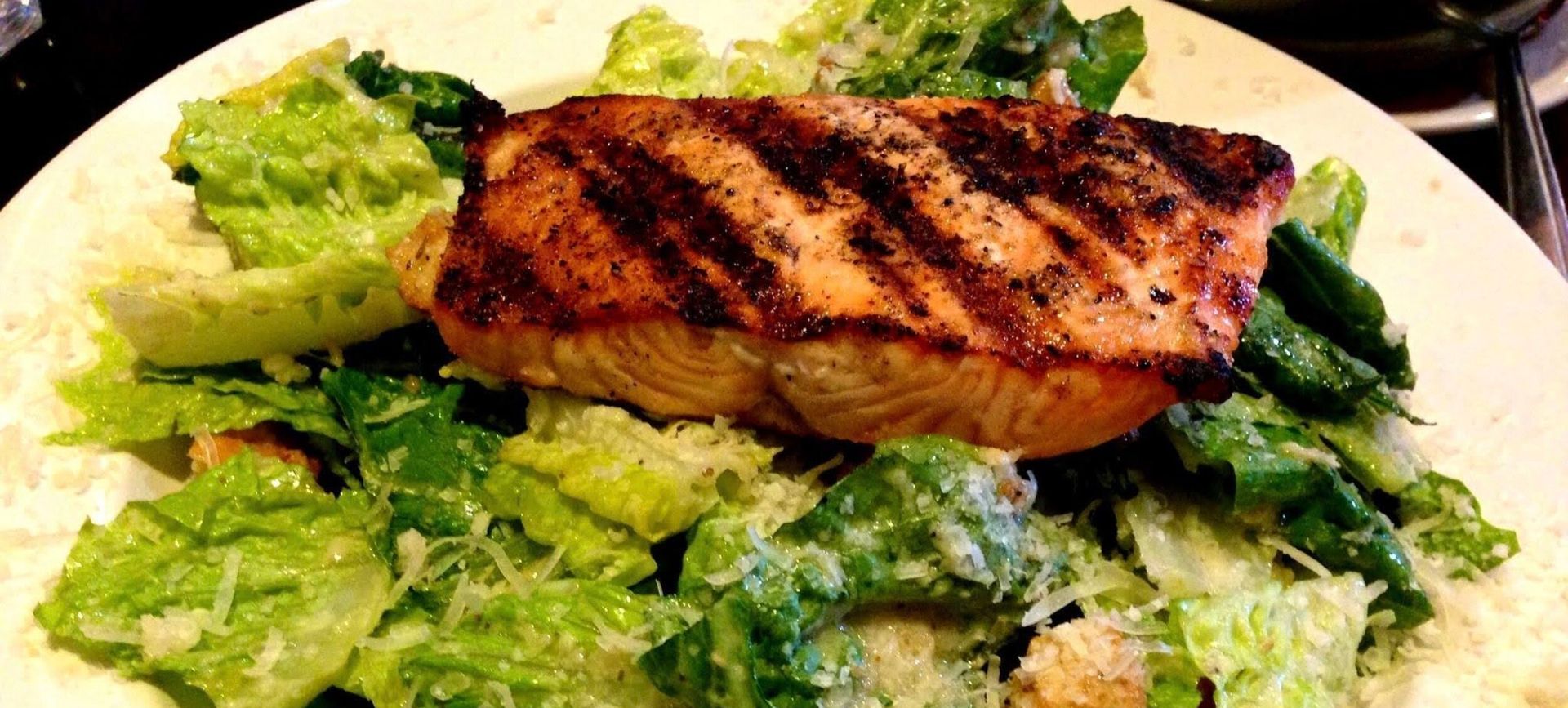 Grilled salmon fillet on a bed of green salad with lettuce and herbs