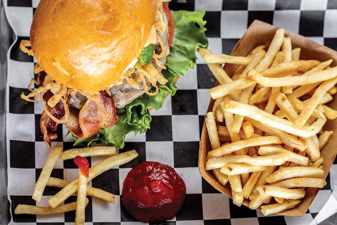 Burger, fries, and ketchup on a black-and-white checkered tray liner.