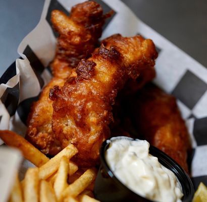 Fried fish with fries and tartar sauce in a paper-lined basket