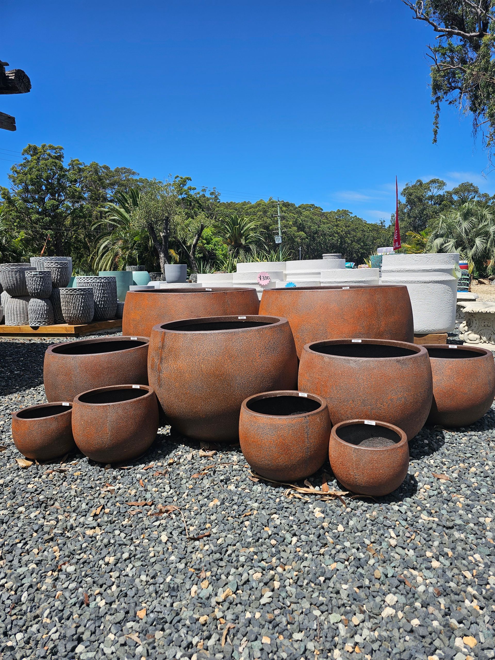 Group of rusty-brown, round, textured planters - Palms Landscape Supplies in Forster, NSW