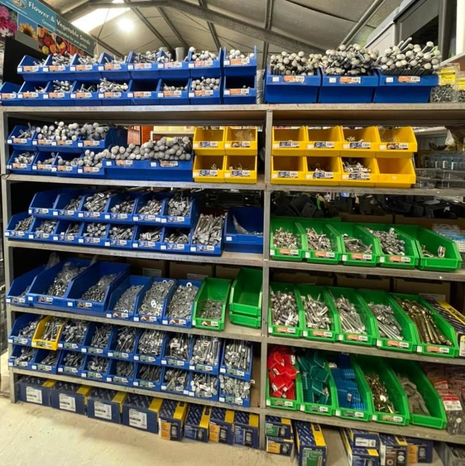 Shelves filled with hardware, bolts, and screws, organised in blue, yellow, and green bins - Palms Landscape Supplies in Forster, NSW