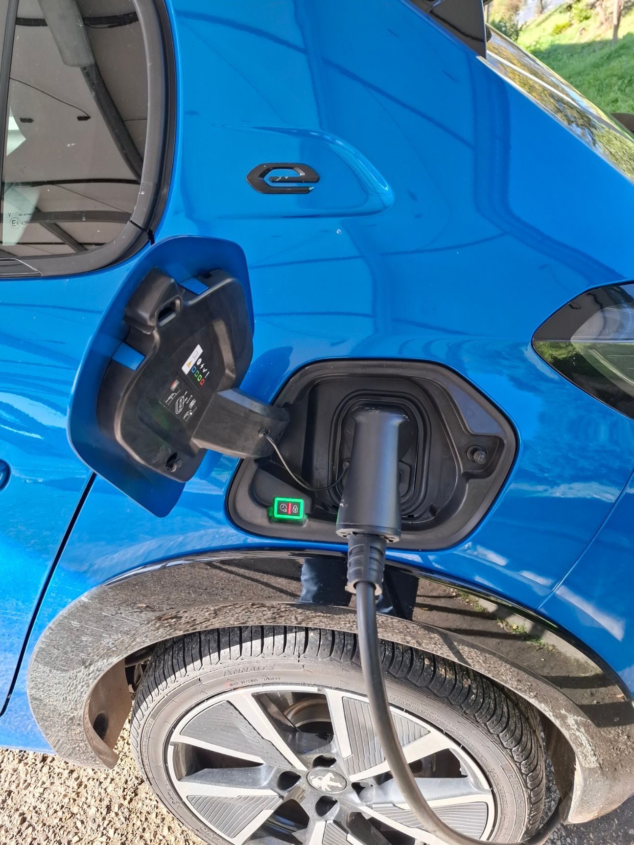 Auto elettrica blu in ricarica, cavo collegato nella parte posteriore.