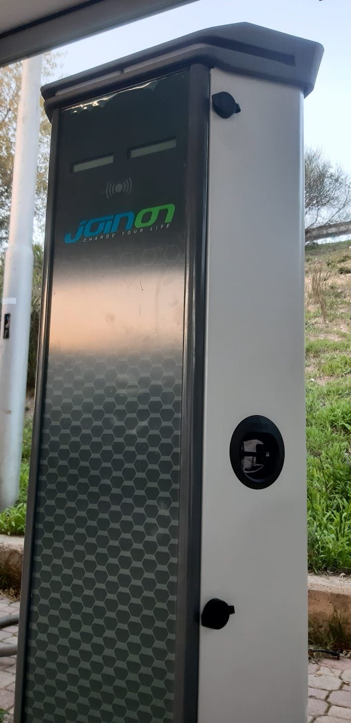Stazione di ricarica per veicoli elettrici con logo verde su pannello frontale in acciaio inossidabile.