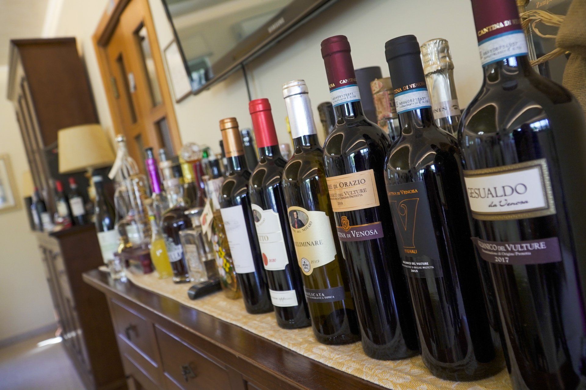 Bottiglie di vino sul bancone di una stanza; un mix di vini rossi, bianchi e di altri tipi.