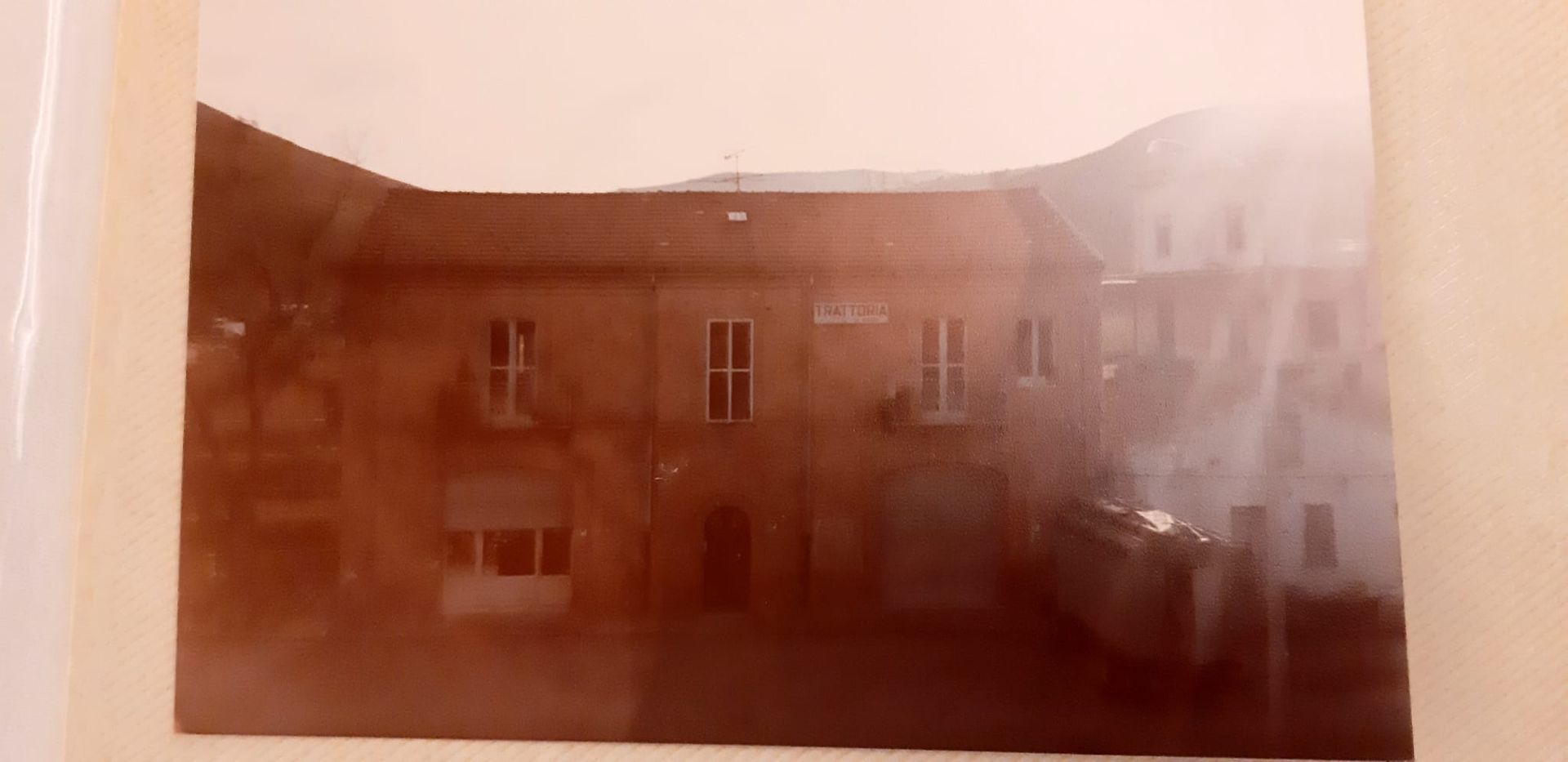 Foto in tonalità seppia di un edificio con finestre e montagne sullo sfondo.