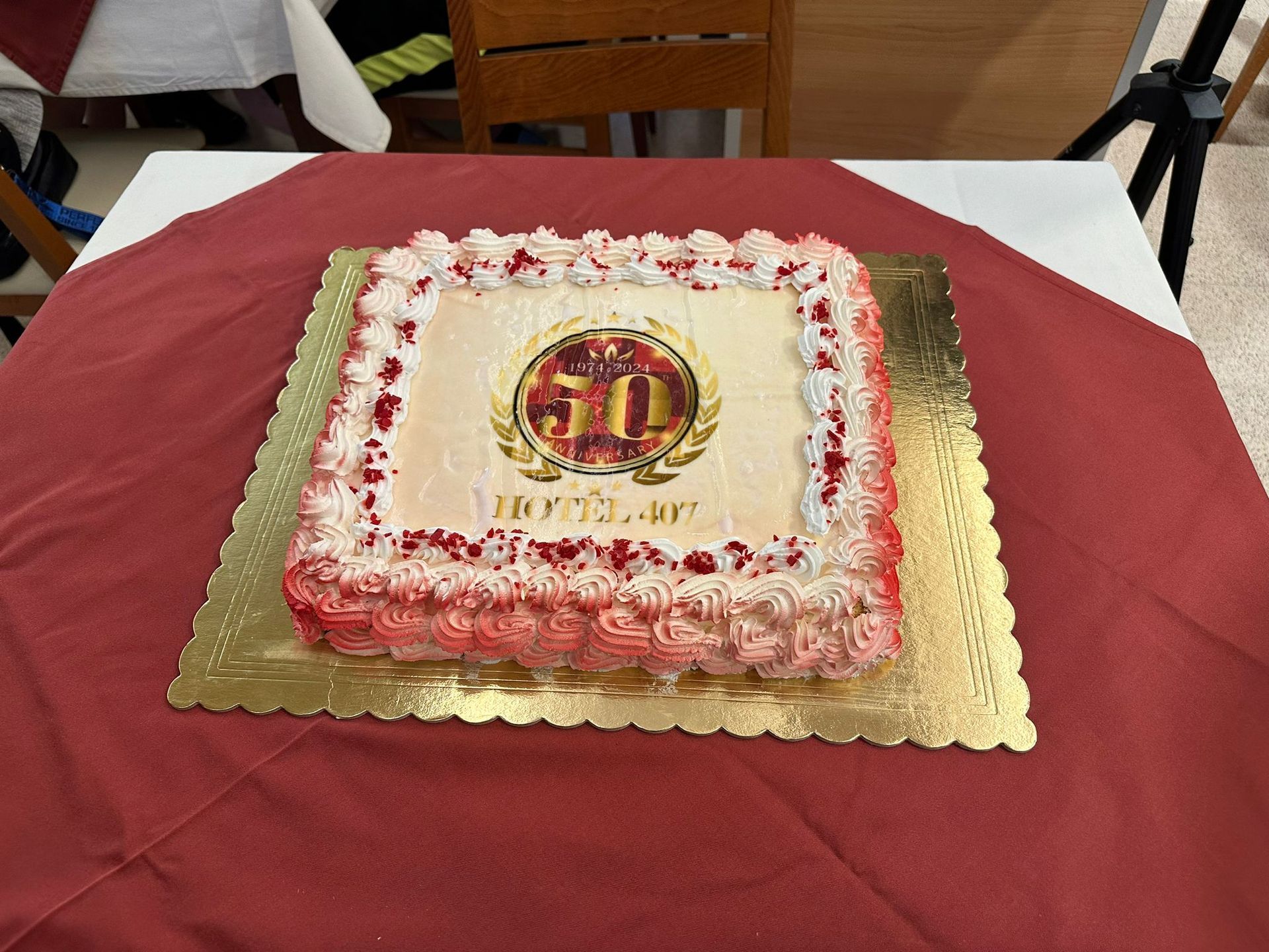 Torta per la celebrazione del 50° anniversario, quadrata, glassata rossa e bianca, con stemma dorato.