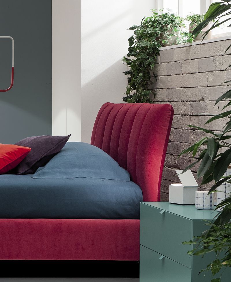 Un letto con testiera rossa e lenzuola blu
