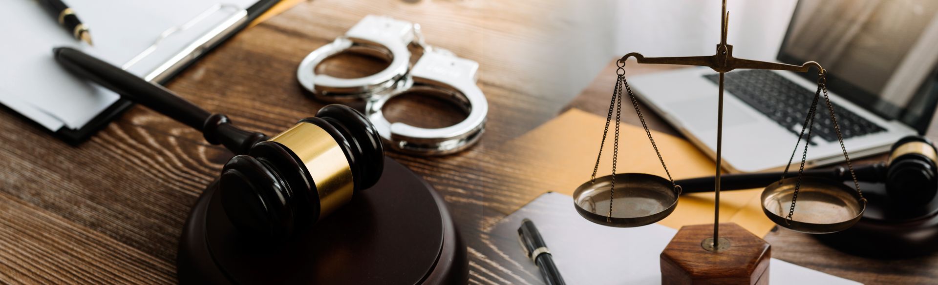 View of wooden gavel, handcuffs, and laptop, representing criminal law.